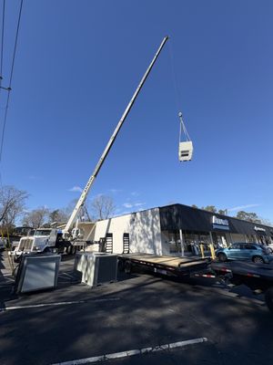 Happy HVAC Solutions installing a 10-ton commercial unit by crane onto a customer's building